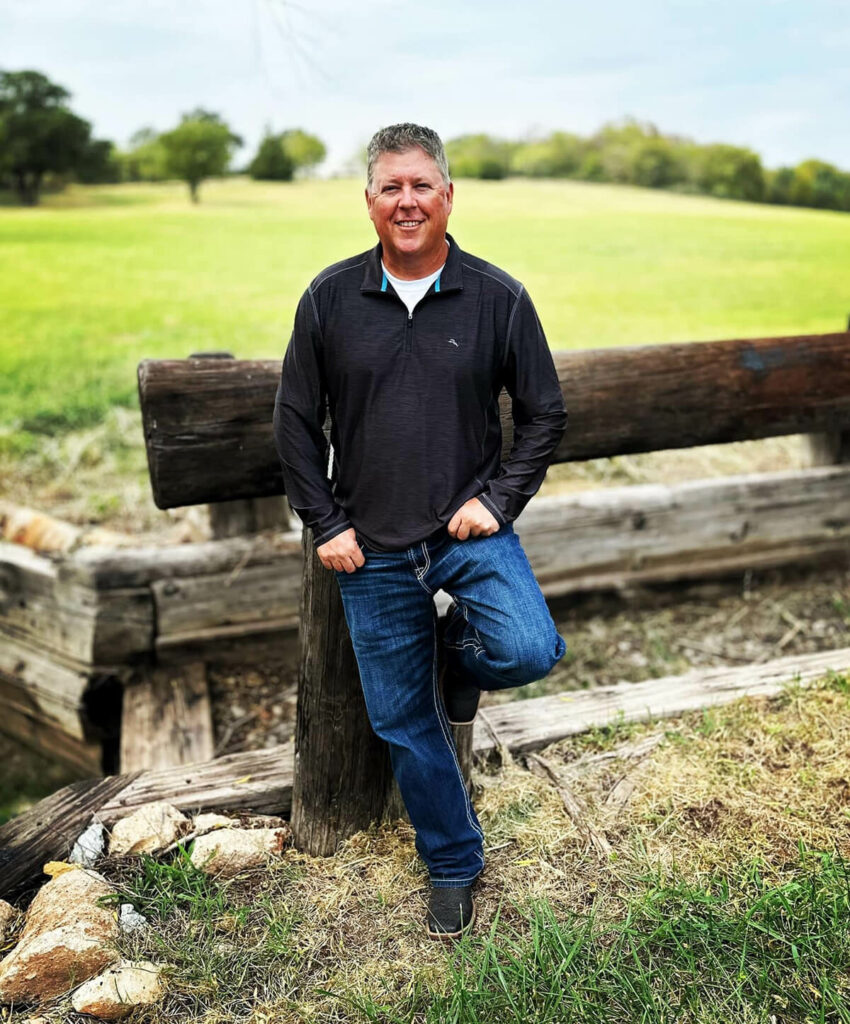 Ronnie Hill leaning against a fence and smiling